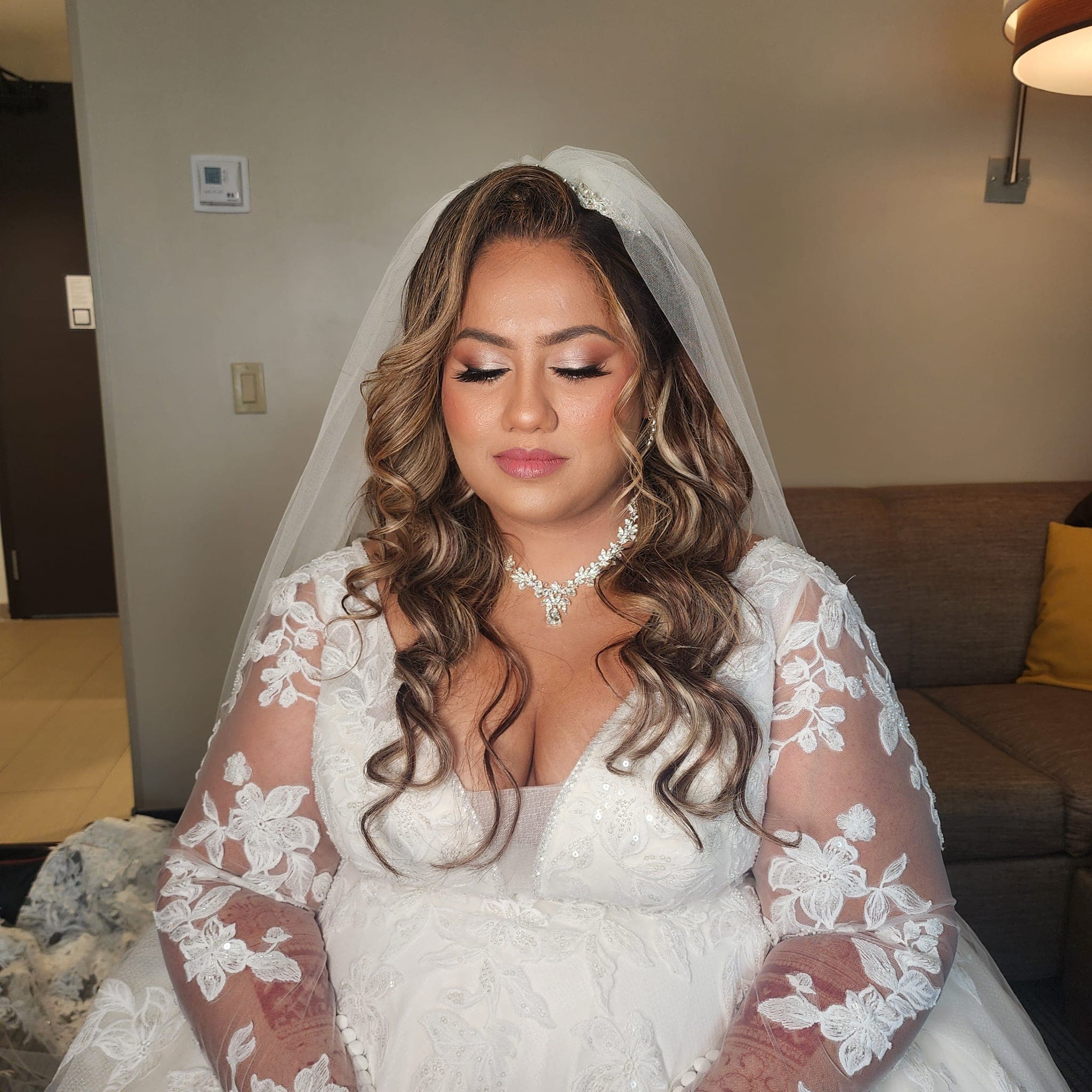 Bridal Makeup & Hair service - A beautiful South Asian bride with elegant traditional makeup, adorned in vibrant red bridal attire with intricate gold embroidery and elaborate jewelry including maang tikka, jhumka earrings, and ornate necklace.